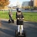 People wearing helmets and riding Segways around a bend